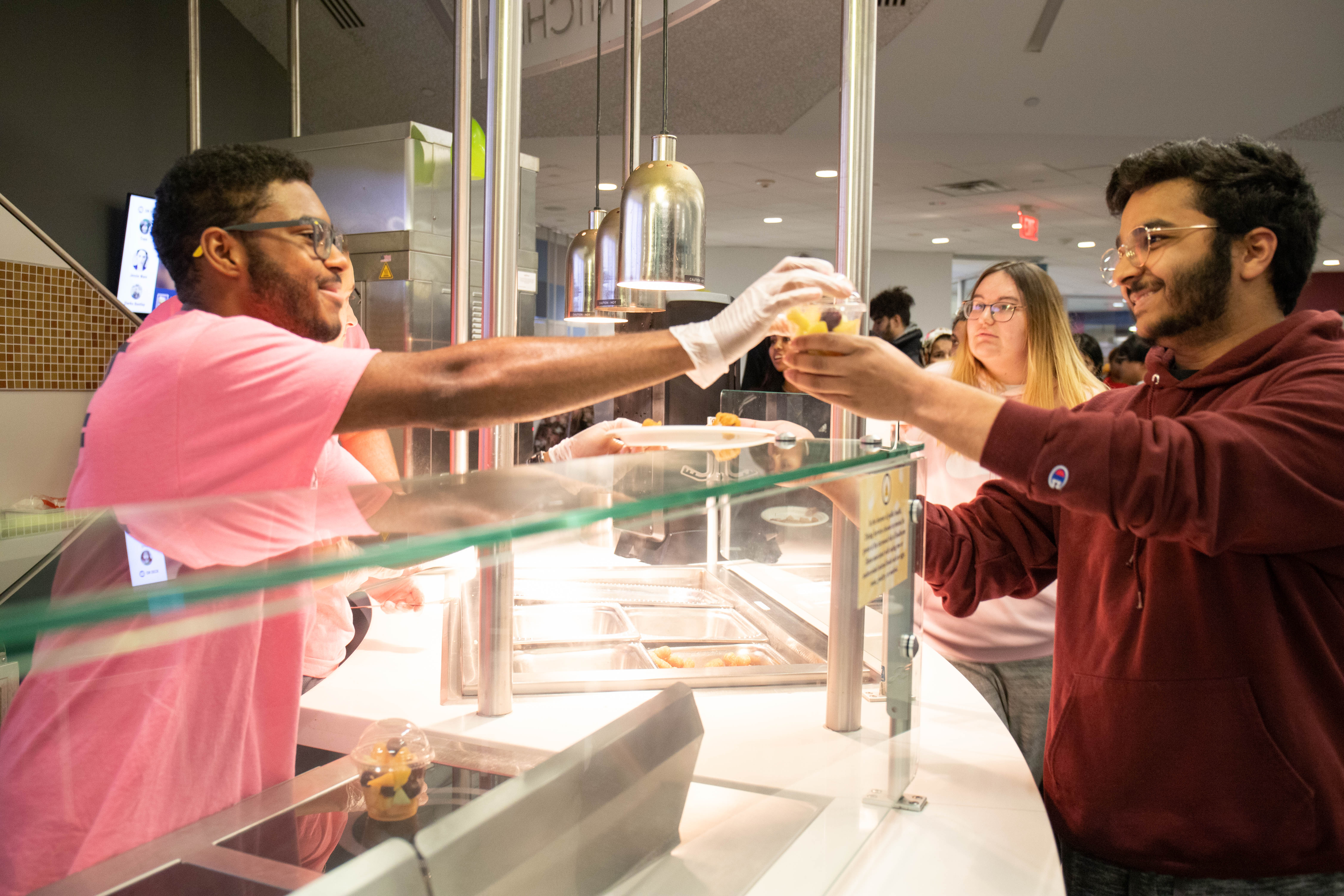 A student grabs a late night snack from volunteer in dining hall