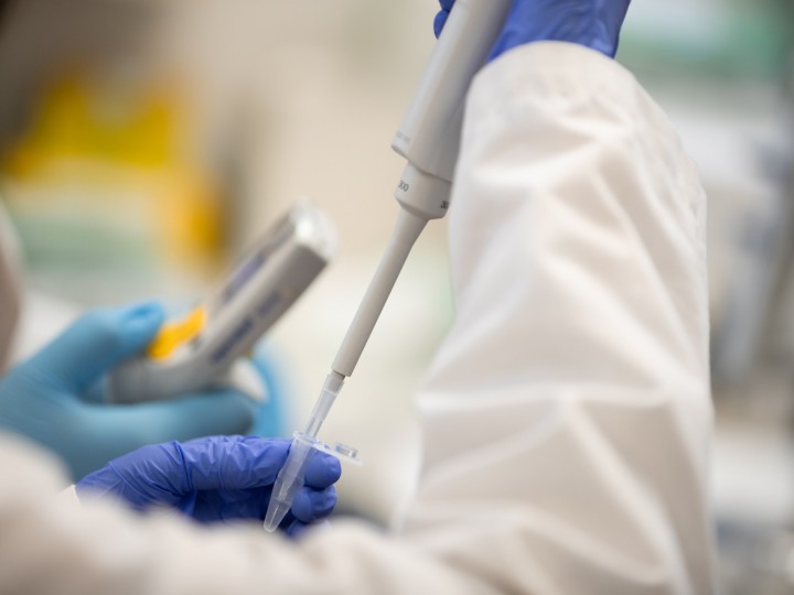 A student holds a pipette with rubber gloves in a lab