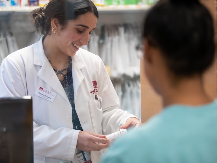 A student works in student operated pharmacy with patient