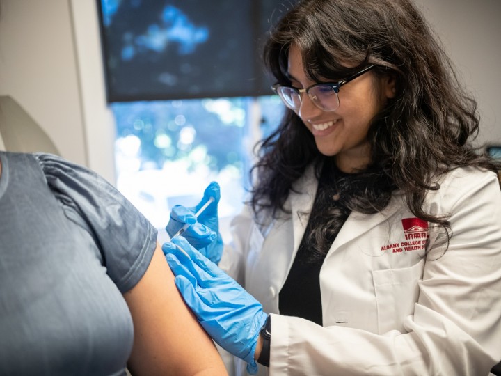A student on rotation gives a patient a vaccine in the arm
