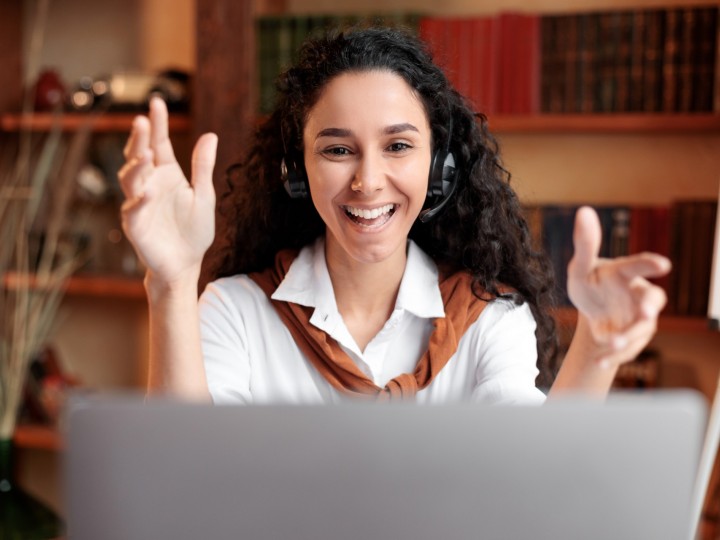 woman at laptop with hands in air smiling