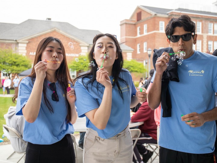 A group of students stand together and blow bubbles at Springfest