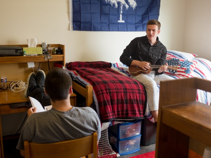 Two students hang out in dormroom and play music