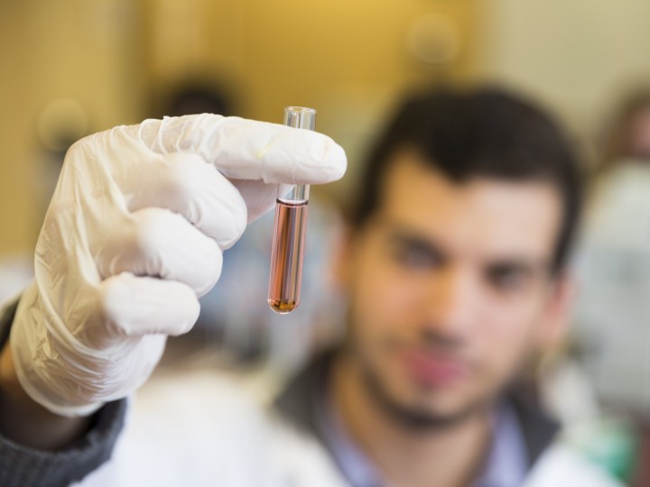 Close up of student holding a test tube filled with red liquid