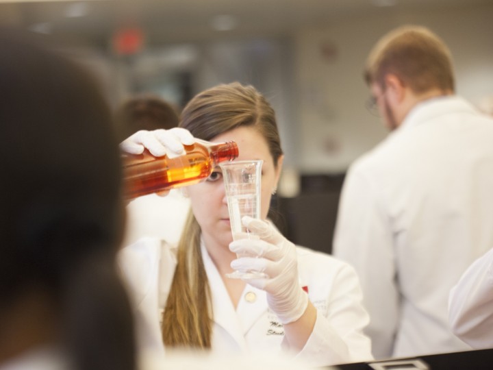 Student pours liquid into beaker during a lab
