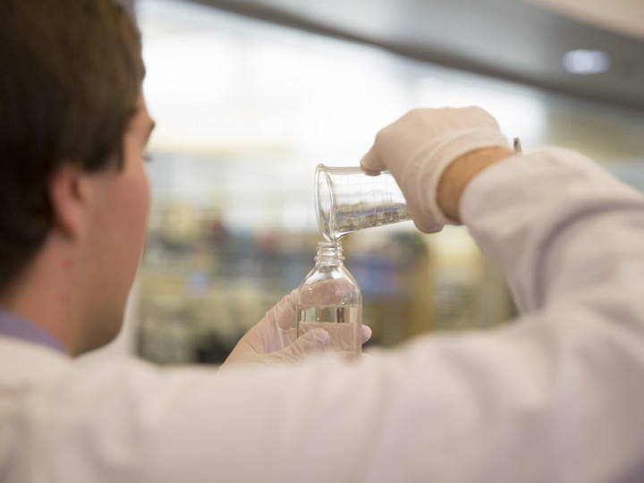 A student measuring wet compounding ingredient with graduated cylinder