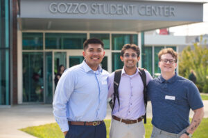 Students dressed professional stand in front of Gozzo student center