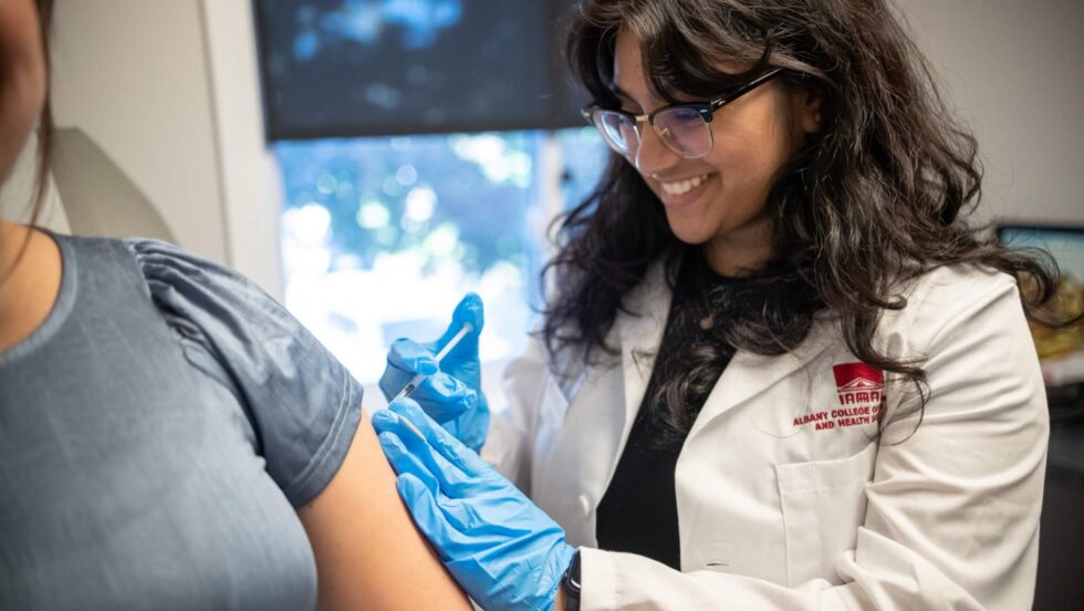 A student on rotation gives a patient a vaccine in the arm