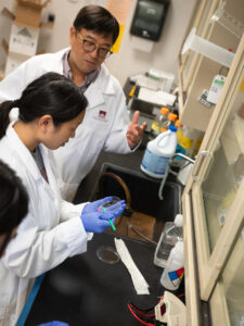 Dr. Kideok with two pharmaceutical sciences students examine petri dish in lab