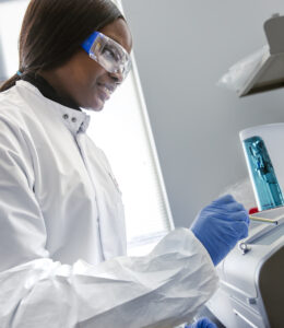 Ejeman Aigbedion works in safety coat, glasses and gloves in CBET lab