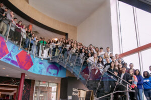 Faculty, staff and students stand together on stairwell in Student Center