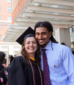 Graduates smile outside on a sunny day
