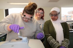 Kendall Rafferty, Madison Burnett and Reem Abdu wear safety goggles in forensic science lab
