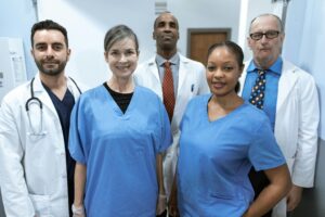 A group of healthcare professionals stand together in scrubs and white coats
