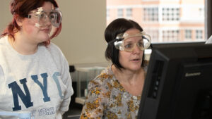 Sara Alvaro and Madison Burnett examine computer with goggles