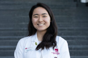 SeHan Jeong in her pharmacy white coat on the stairs at the Gozzo Student Center