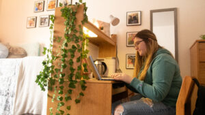 Student sits at desk with laptop in dorm room