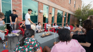 Students gather around fire pit with marshmallows