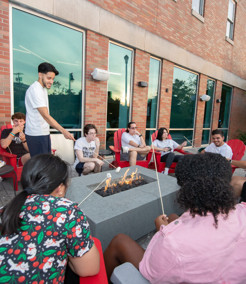Students gather around fire pit with marshmallows