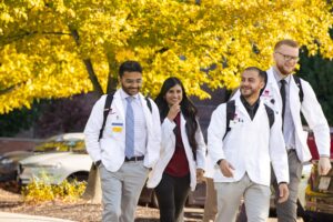 Students in white coat with yellow fall foliage