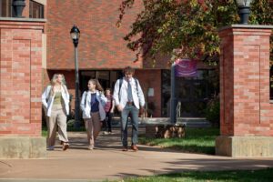 Students walk out of O'Brien building wearing white coats