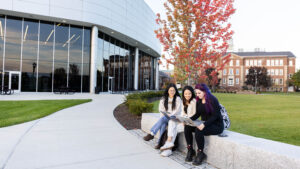 Students sit on stone wall outside