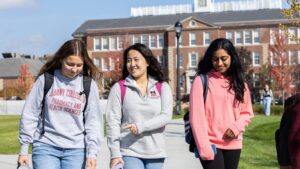 Three students walk on campus during a Fall day
