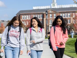 Three students walk on campus during a Fall day