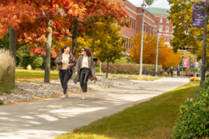 Two students walk across campus on a beautiful Fall day