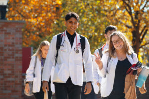 Two students in white coats walking on campus