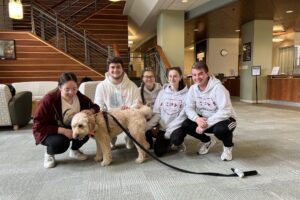 five students de-stressing with a therapy dog 