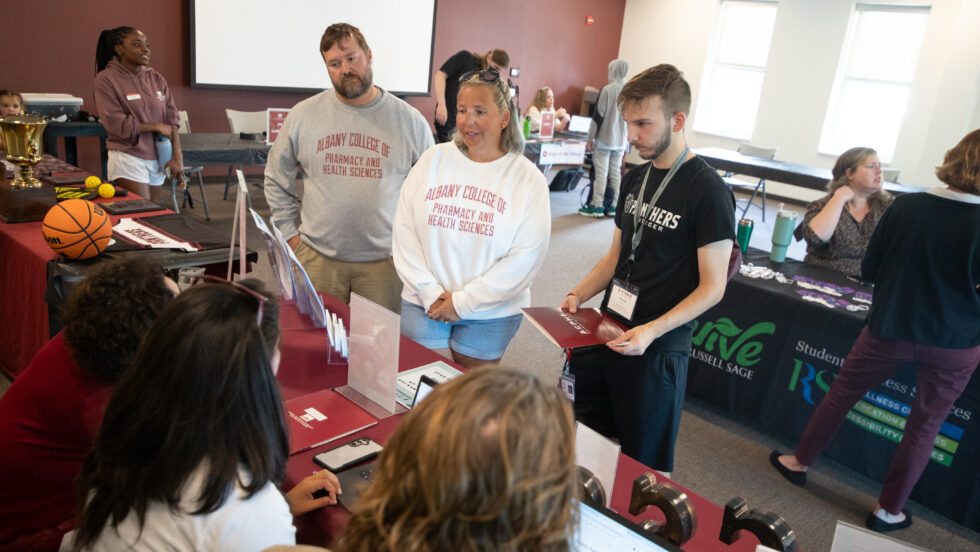 Parents stand with student at table during Move In Day