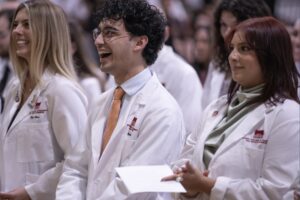 Students smile in crowd at white coat ceremony