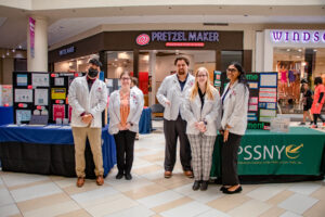 Students stand in front of tables at health expo