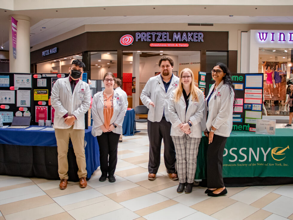 Students stand in front of tables at health expo