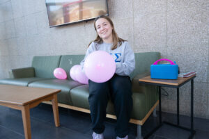 A female student holds a pink balloon as the club Colleges Against Cancer decorate the atrium for Breast Cancer Awareness Month