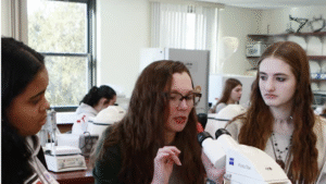 Professor Nicole Shakerley helps a student look through a microscope