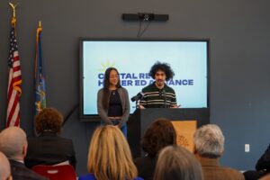 Ron Espinal speaking at the mic with Jasmin Martinez