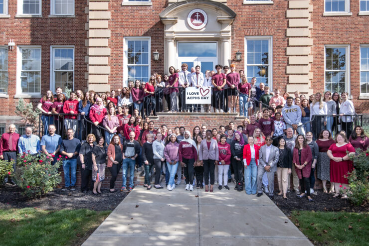 A group of ACPHS campus members stand on front of the library on I Love ACPHS Day in 2023