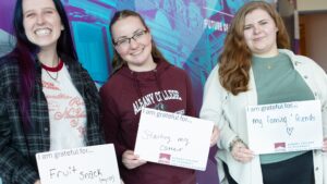 PharmD students holding signs that state they are grateful for their cat FruitSnack, for staying their career and for family and friends
