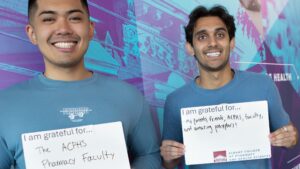 PharmD students holding signs that stating they are grateful the ACPHS Pharmacy faculty and their parents, friends, and faculty