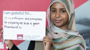 A PharmD student holds a sign which say she is grateful for all of my professors and preceptors for preparing me to be a great pharmacist
