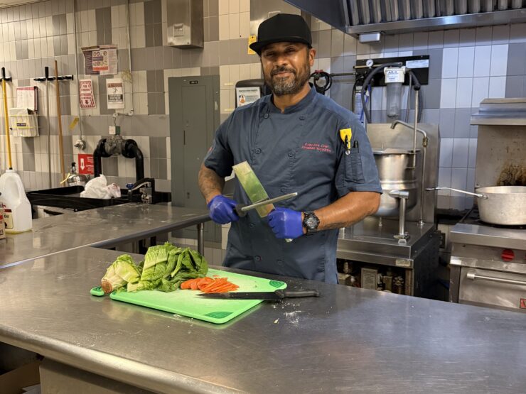 Chef Jonathan holds a knife and sharpener in the kitchen